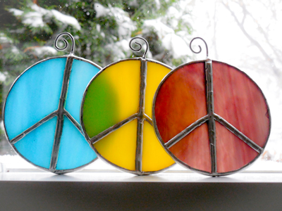 Stained glass peace sign suncatchers in a window.
