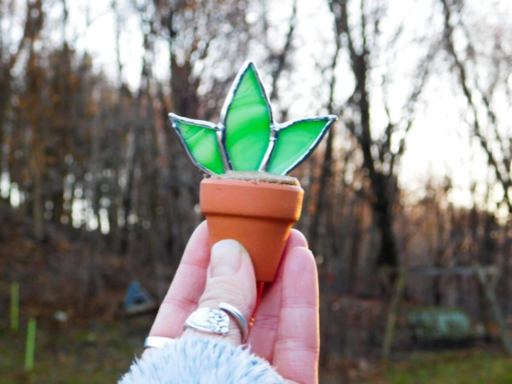 hand holding stained glass aloe succulent in terra cotta pot