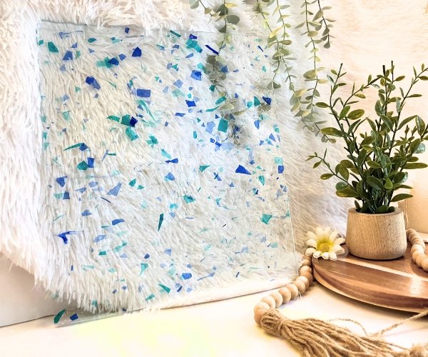 Designer Glass Blue Aqua Fracture stained glass sheet with flecks of blue and aqua on clear with plant in front Mountain Woman Products
