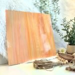 Oceanside White Orange Opal stained glass sheet with streaks or white and orange with a furry white background and plant in Mountain Woman Products studio