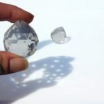Fingers holding Crystal Ball Glass Prism with another in the background Mountain Woman Products