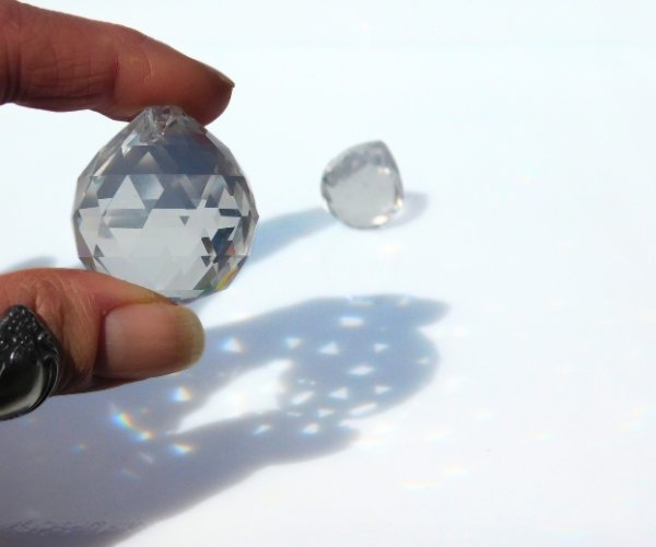 Fingers holding Crystal Ball Glass Prism with another in the background Mountain Woman Products