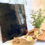 DG1068 Amber Chocolate Streaky Stained Glass Sheet with a plant and daisies in the foreground in Mountain Woman Products studio