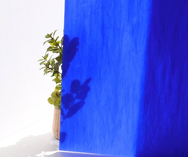 DG1105 Designer Dark Blue White Stained Glass Sheet showing cobalt blue color with plant behind it to see opacity Mountain Woman Products