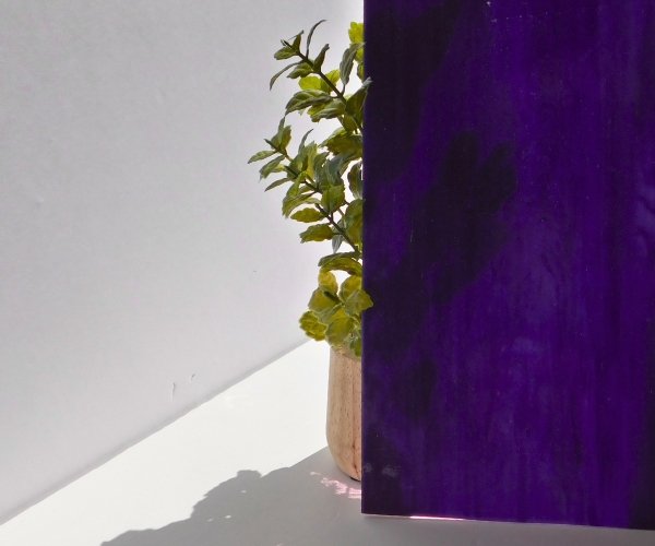 DG1129 Designer Iridized Purple White Clear Stained Glass showing the opacity of the glass which is minimal with a plant behind it Mountain Woman Products