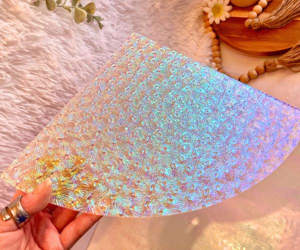 Dichroic Florentine Rainbow 1 Thin on Clear Glass held by a hand with beads and a fur and iridescent background Mountain Woman Products