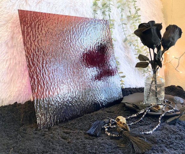 Oceanside Light Purple Rough Rolled stained glass sheet in front of a white fur background and black base with black roses in Mountain Woman Products studio