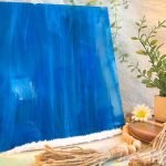 Oceanside Deep Aqua White Wispy Stained Glass Sheet is a darker blue color with white streaks with a plant and daisies in the foreground Mountain Woman Products