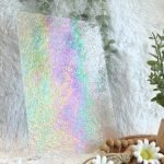 Wissmach Iridized Clear Dew Drop Stained Glass sheet with a fuzzy white background and a plant in the Mountain Woman Products studio