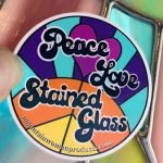 Peace Love Stained Glass sticker written in hippie font with sun with peace sign in it and heart in the background from Mountain Woman Products