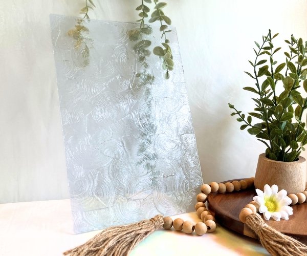 Kokomo Rondalite Clear Stained Glass sheet with plant and daisy in the background in the Mountain Woman Products studio