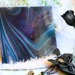 Oceanside Phantom Galaxy Stained Glass with purple blue and white swirls and aventurine sparkly bits with a black rose and a white background in the Mountain Woman Products studio