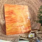 Designer Glass Orange Yellow Red against a woven background with a plant DG1158 at the Mountain Woman Products Studio