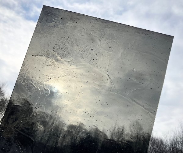 Designer Glass Grey Transparent Stained Glass Sheet a see through cathedral charcoal colored sheet up against a cloudy sky at the Mountain Woman Products studio