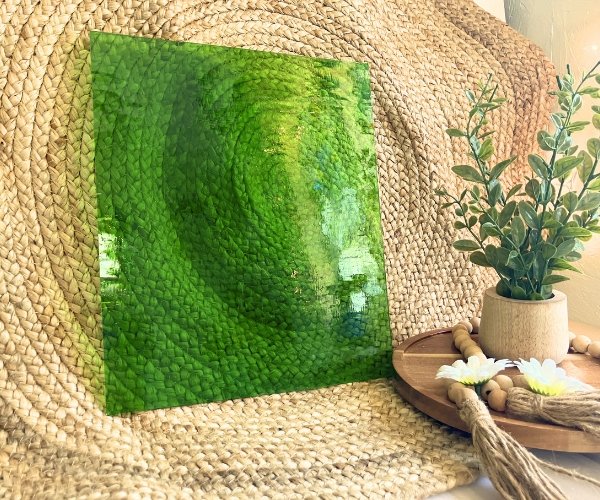 Designer Glass Medium Green Transparent Fusible COE 96 glass sheet in front of jute fabric with a plant for comparison in the Mountain Woman Products studio