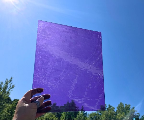 Designer Glass Light Lavender Fusible Stained Glass Sheet showing a bluey purple cathedral glass held in hand with a sky in the background at the Mountain Woman Products studio
