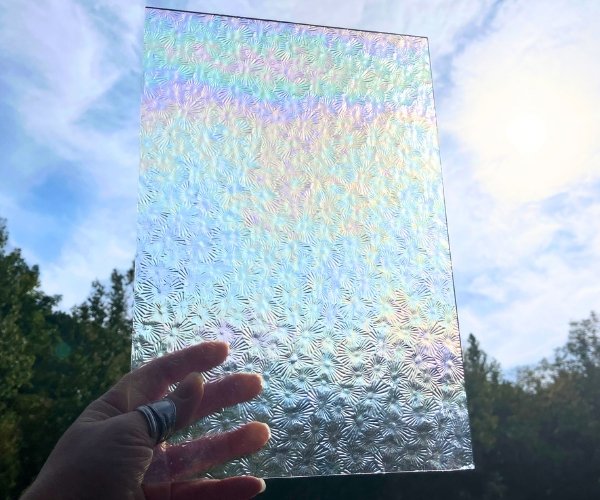 Wissmach Iridized Florentine Stained Glass Sheet held in front of the sky at the mountain woman products