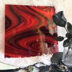 Oceanside Ember Black on Red Fuser's Reserve Limited Edition Stained Glass Sheet showing black swirls on transparent red glass on a white background with black roses in front in the mountain woman products studio